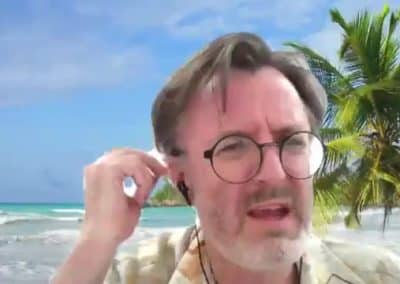 Frédéric Bouquet lors d'une visio conférence avec une plage paradisiaque comme fond d'écran