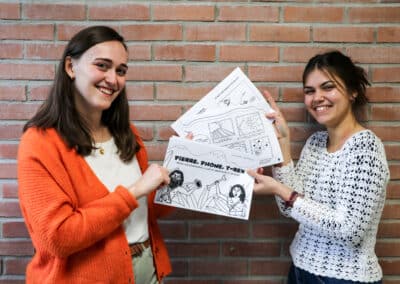 Deux étudiantes souriante et de face exposent des feuilles en papier