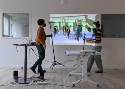 Deux femmes manipulent un portant métallique dans une salle de classe et face à un écran