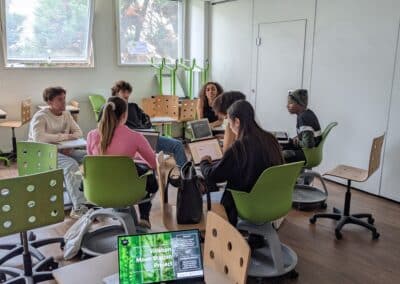 Des étudiants munis d'ordinateurs sont assis et travaillent collaborativement