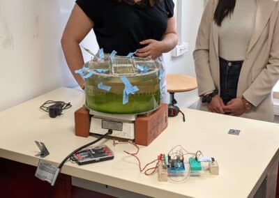 Deux étudiantes face à une boîte transparente contenant un liquide verdatre lors d'une expérience de physique