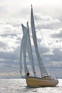 Voilier voguant sur l'eau toutes voiles dehors sous un ciel nuageaux